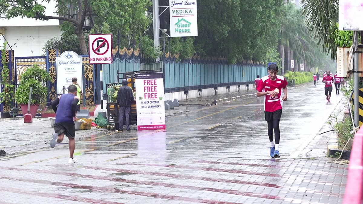 A runner passes a tender coconut cart and a banner reading Free Free Free, Tender Coconut, Free for Runners, on the Cardiac Rehab Run 2026 route